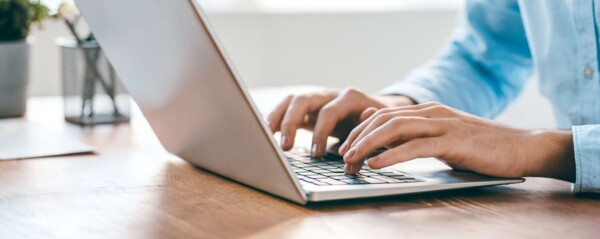 Person tippt auf die Tastatur eines Laptops